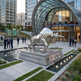 Metallic bull statue in front of a modern building with financial-themed elements.