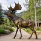 Bronze moose statue on a pathway with trees and mountains in the background