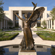 Bronze statue of a woman with wings holding a bird in front of a building