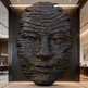 Large black stone sculpture of a face in a modern interior setting