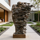 Bronze sculpture of a dynamic figure in an outdoor setting with modern 
architecture.
Bronze statue of a human figure transforming into ribbon‑like strips