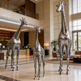 Three metallic giraffe sculptures in a hotel lobby.
Polished metal giraffe sculpture set with tall, medium, and small figures