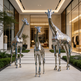 Three metallic giraffe sculptures in front of a modern building entrance.
Reflective metal giraffe artwork with stylized textures and smooth contours