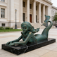 Bronze mermaid statue in front of a classical building