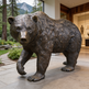 Bronze statue of a bear in an indoor setting with a mountainous background