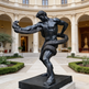 Statue of a muscular figure holding a snake in an elegant courtyard with classical architecture.