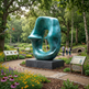 Large blue sculpture in a garden setting with people and nature around
