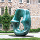 Large greenish-blue sculpture in front of a stone building