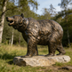 Bronze bear statue on a rock with trees in the background