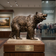 Bronze bear statue on display in a museum with visitors in the background