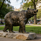 Bronze bear statue in a park with people and trees in the background