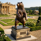 Bronze bear statue in a formal garden with classical architecture in the background