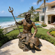 Bronze statue of a mythological figure on a turtle by a house with a pool and ocean view.