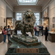 Bronze lion statue in a museum with visitors around