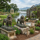 Bronze lion statues in a park setting with a lake and mountains in the background.