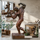 Bronze sculpture of a muscular figure in a modern indoor setting with 'MIND | BODY | SPIRIT' text.