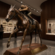 Bronze sculpture of a horse and rider in a museum setting