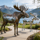 Bronze and silver moose statues with a mountain and lake background