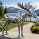 Reflective moose sculpture in a scenic outdoor setting with mountains and water.