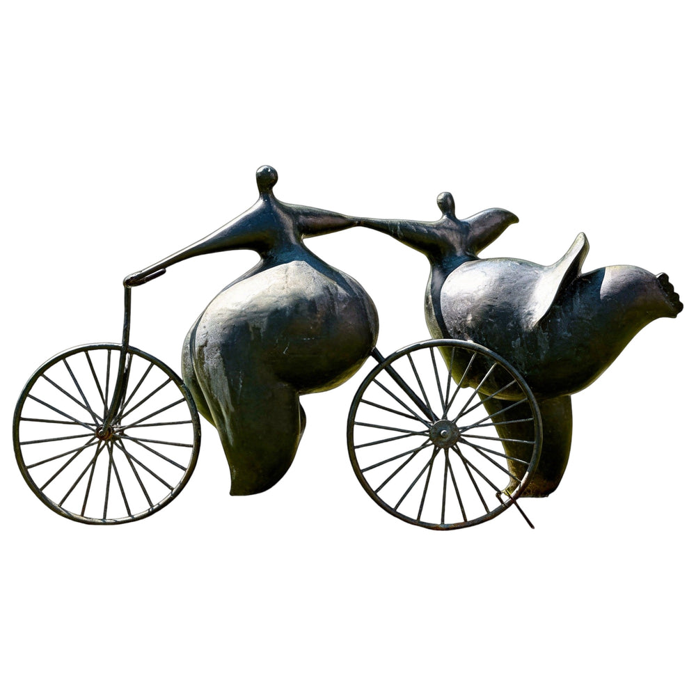 Bronze abstract sculpture of two stylized human figures riding bicycles, featuring rounded forms and dynamic motion