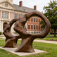 Dual‑figure bronze sculpture with fluid curves and circular voids representing open‑mind concepts