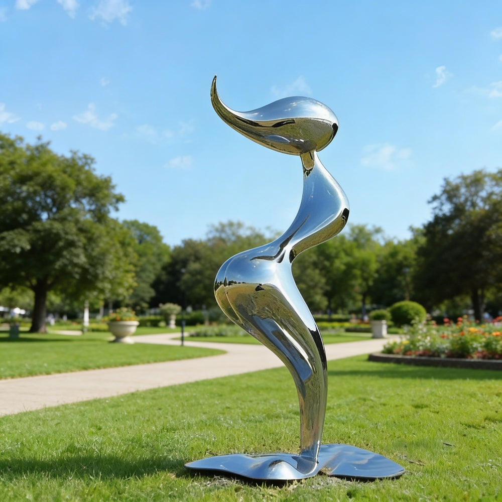 Silver abstract sculpture on grass with trees and sky in the background