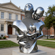Metallic sculpture of two embracing figures in front of a building