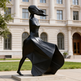 Black abstract sculpture in front of a classical building

Modern metallic sculpture depicting an elongated female figure in motion