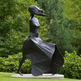 Statue of a woman with outstretched arms and flowing dress in a garden 
setting
Elegant abstract female sculpture with elongated lines and motion‑inspired design