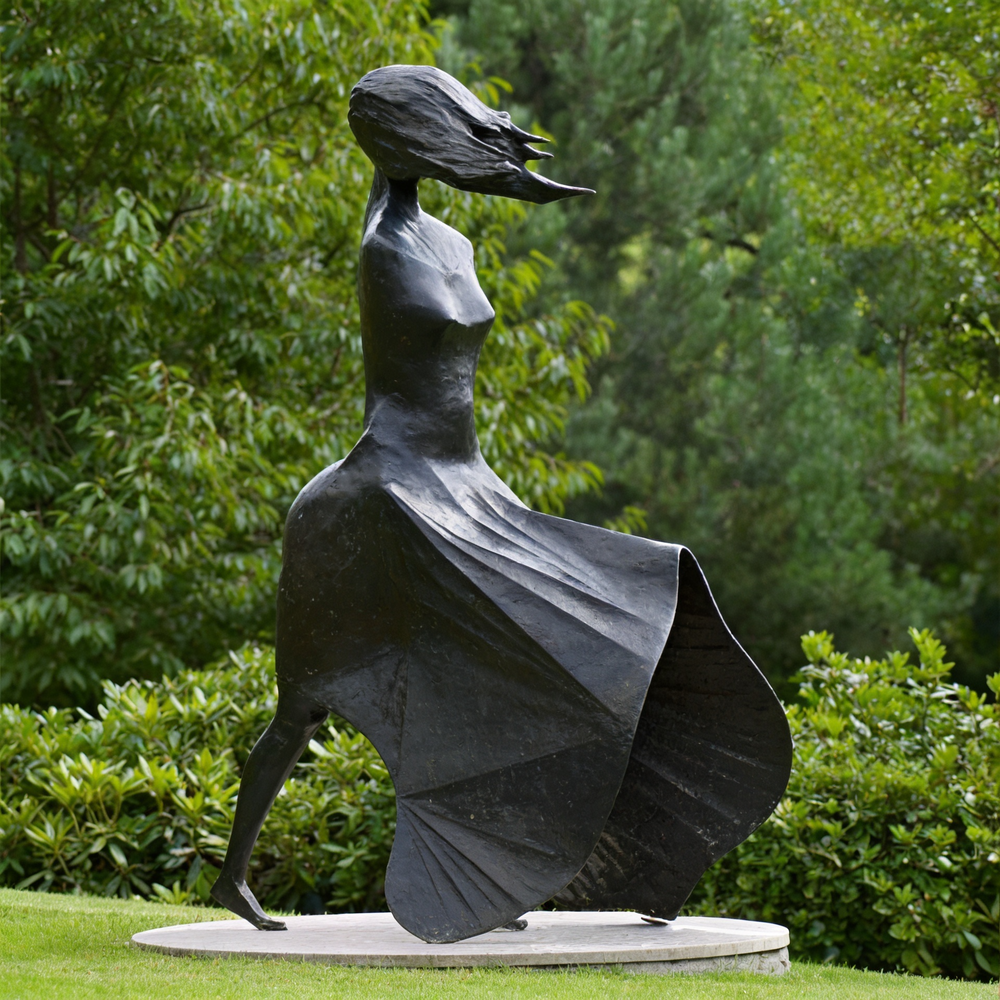 Statue of a woman with outstretched arms and flowing dress in a garden 
setting
Elegant abstract female sculpture with elongated lines and motion‑inspired design
