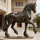 Polished bronze horse figure standing on a circular base in a prancing pose