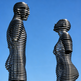 Reflective metallic artwork featuring ring‑layer human silhouettes facing each other