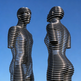 Two metallic sculptures of human figures against a clear blue sky

Modern abstract sculpture with two figures built from horizontal metal ring