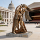 Abstract bronze‑tone sculpture featuring elongated geometric figures in an embrace