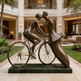 Bronze sculpture of a couple on a bicycle in an outdoor setting with a building in the background
Romantic bronze sculpture featuring a cyclist and abstract partner