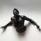 Black sculpture of a muscular figure on a white background