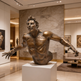 Bronze statue of a muscular figure in a gallery setting