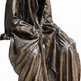 Bronze statue of a draped figure on a white background
