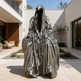 Statue of a hooded figure in a modern outdoor setting
Sculpture of a seated cloaked figure with mysterious faceless design
