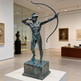 Bronze warrior statue posed in a dynamic archery stance