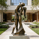 Bronze sculpture of a couple embracing in an outdoor setting with a building in the background