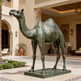 Bronze statue of a camel in front of an elegant building with decorative architecture.