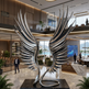 Large metallic sculpture of wings in a modern office lobby with 'AURUM' branding.