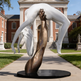 Expressive sculpture of a bronze arm elevating a smooth white figure, symbolizing support and motion