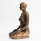 Wooden sculpture of a seated figure on a white background