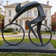 Sculptural cyclist rendered in modern angular shapes, leaning forward in a racing stance