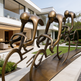 Bronze sculpture of cyclists on bicycles in front of a modern house