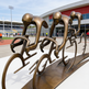 Bronze sculpture of cyclists in a line at an outdoor sports facility
