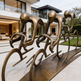 Bronze sculpture of cyclists in a line outside a modern house
