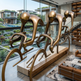 Bronze sculpture of four figures in a modern living room with a view of a pool and garden.
